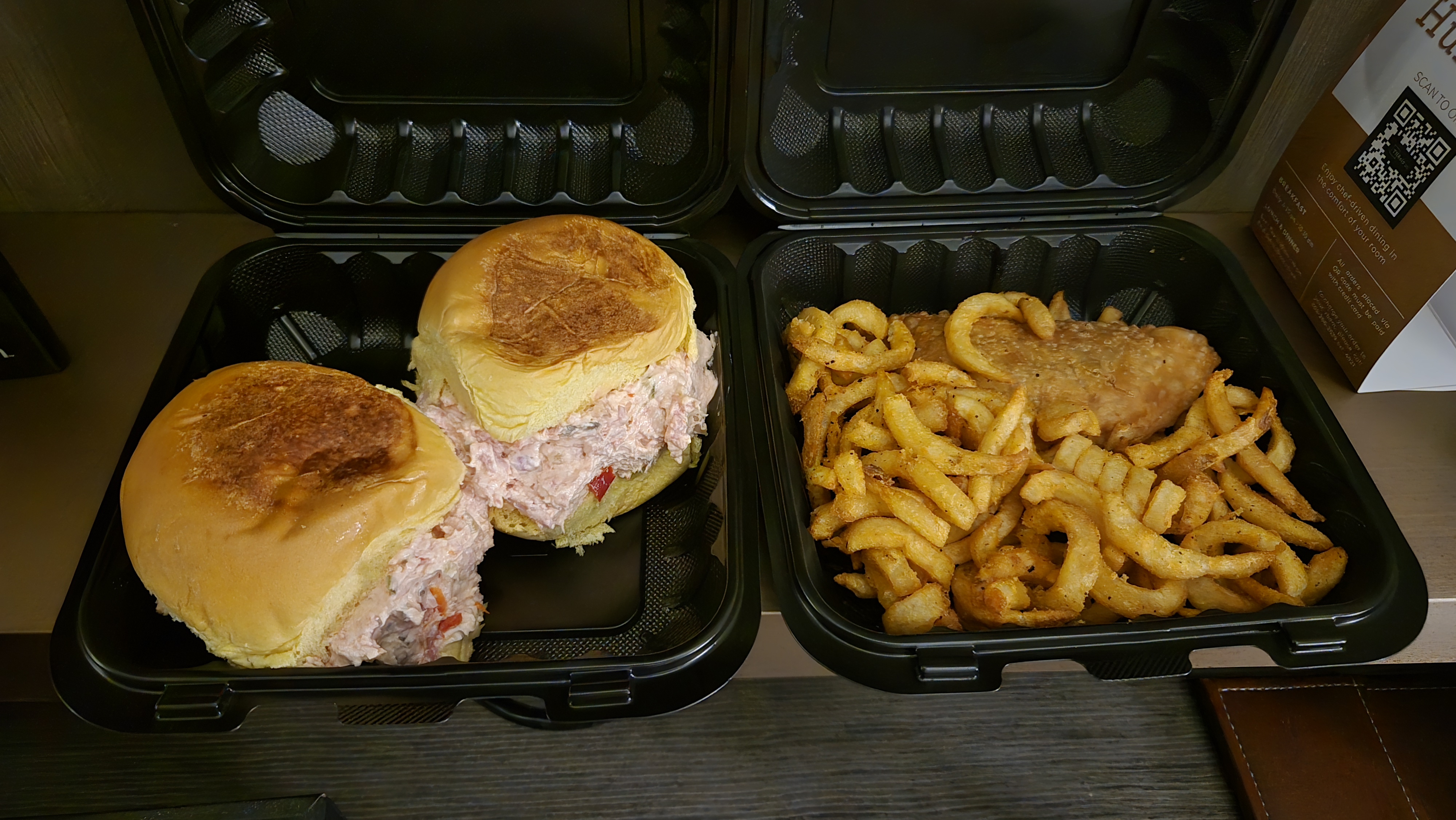 A pair ground ham sandwiches and a box filled with curly fries and an empanada.