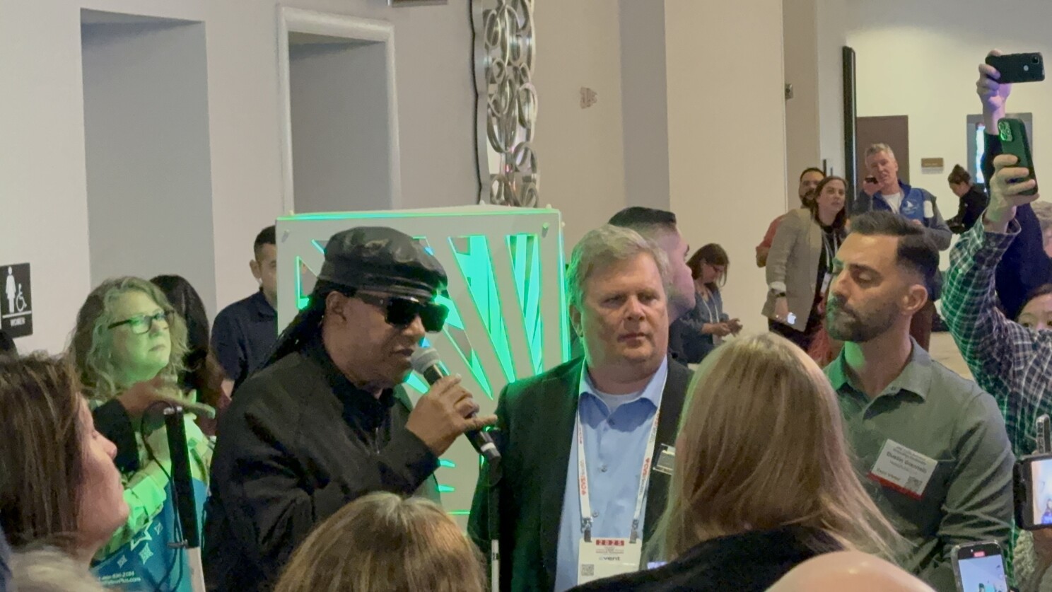 Stevie Wonder, holding a microphone, surrounded by fans at CSUN.